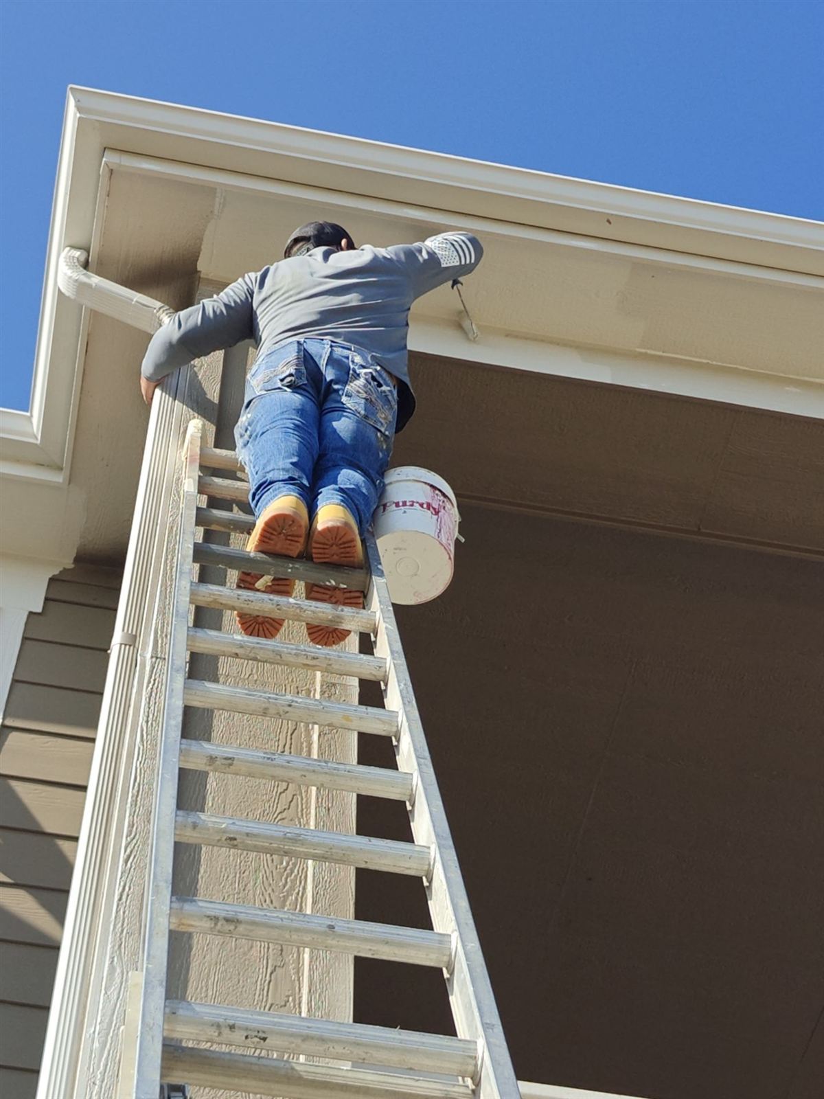 Painter on a lift painting second-story soffits on a home in Arvada